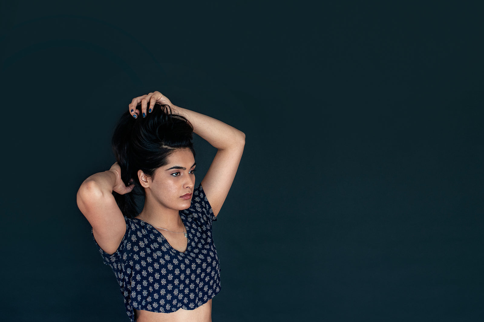 A woman in a quiet moment, hair held in her hands